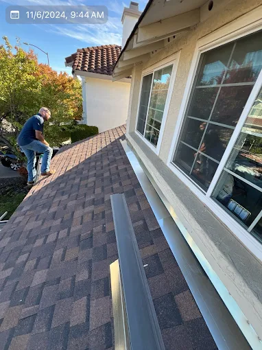 Peak Edge Roofing crew member installing gutters and flashing on a residential roof