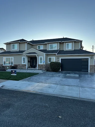 Two-story home with new dark architectural shingle roof at dusk