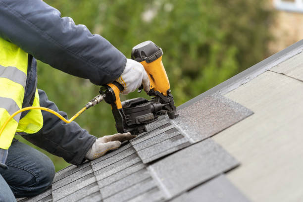 Close-up of a roofer nailing down architectural shingles with a nail gun
